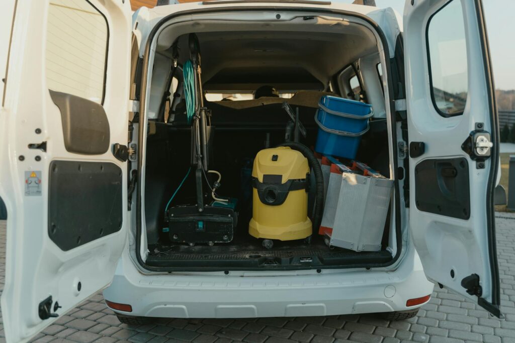 Photo by Tima Miroshnichenko A van with cleaning supplies reveals its open trunk filled with tools and equipment.