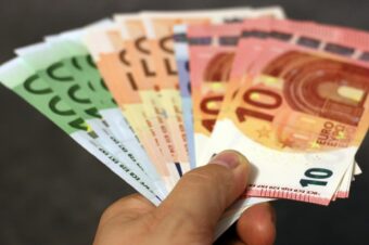 A fan of euro banknotes in various denominations held in a hand.