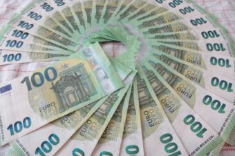 Close-up of a fan of 100 euro banknotes arranged in an artistic circle pattern on a textile surface.